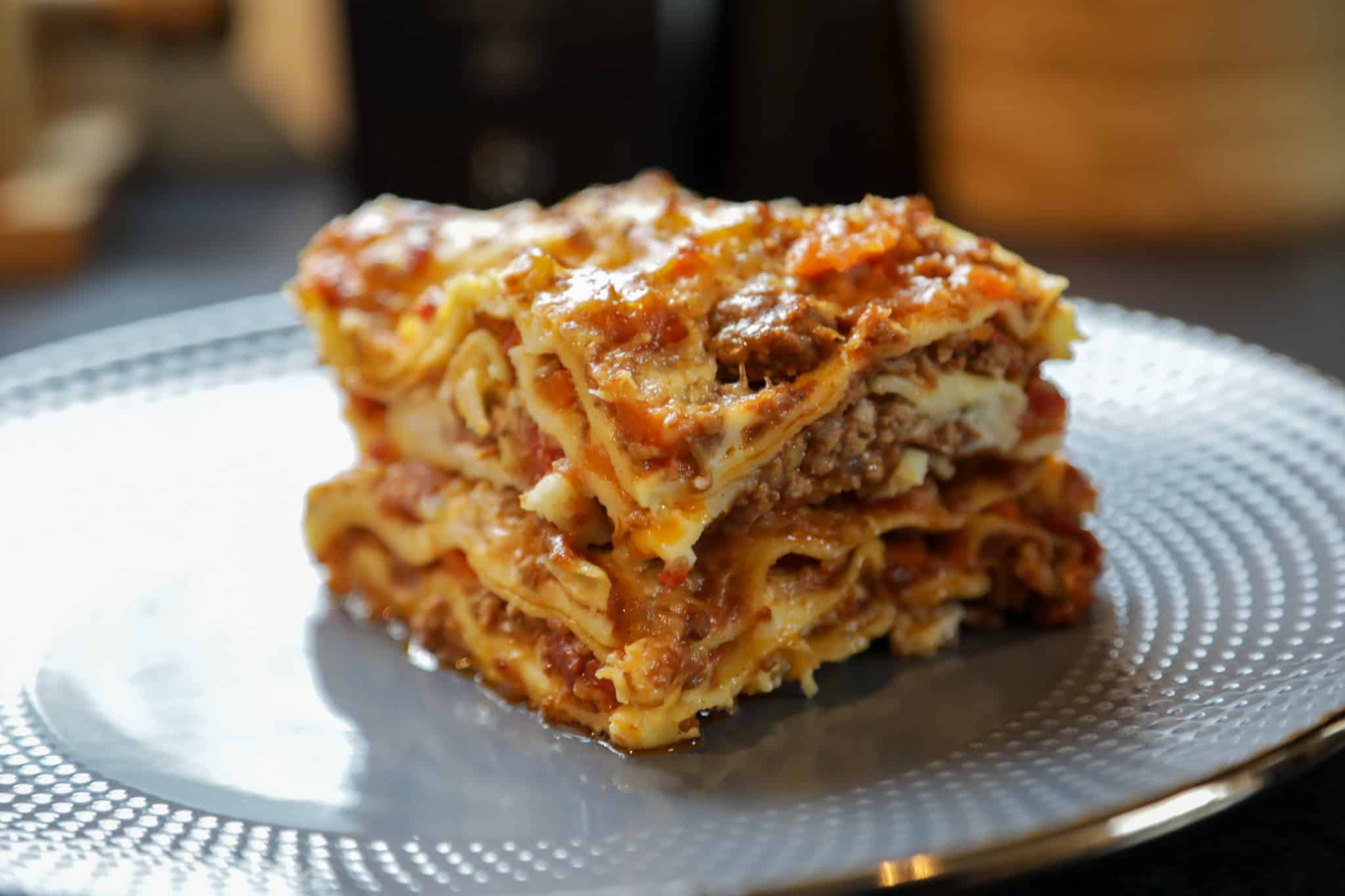 Klassisk lasagne med kjøttsaus og béchamel, servert på grå tallerken